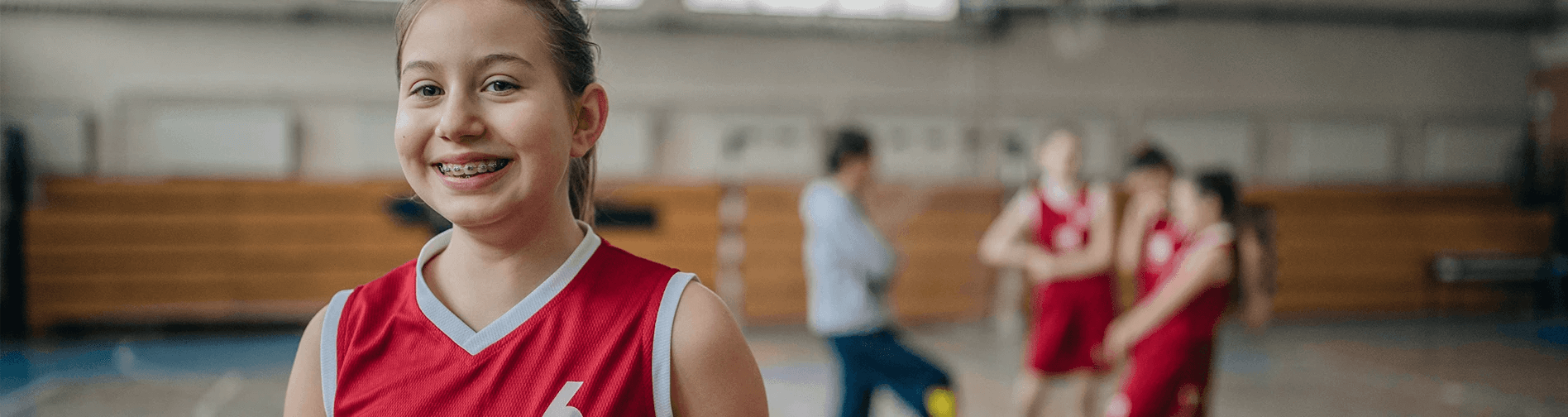 young girl with braces smiling on basketball court