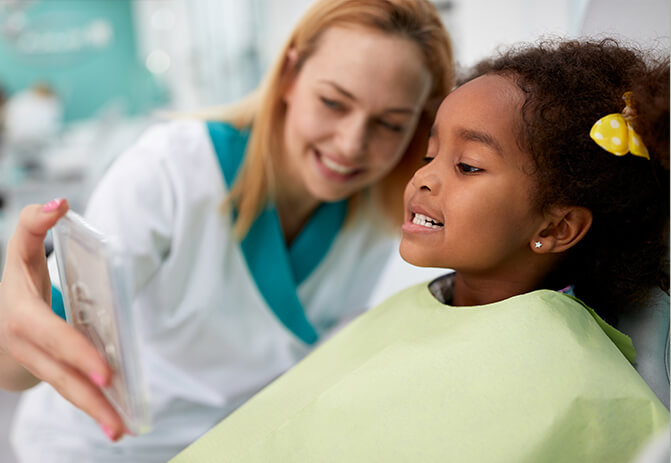 young girl looking at teeth at the dentist